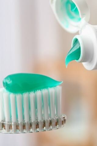 Toothpaste being squeezed out onto a toothbrush