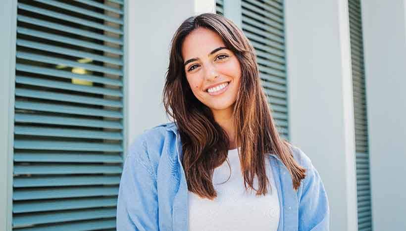 Woman with white teeth smiling while standing outside