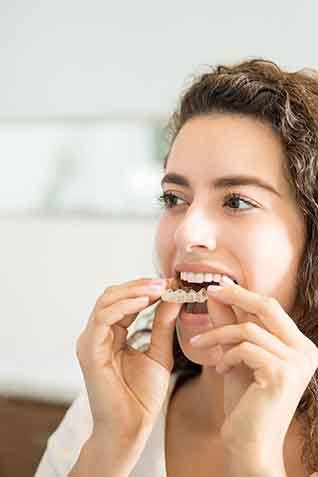 Smiling patient putting clear aligner on