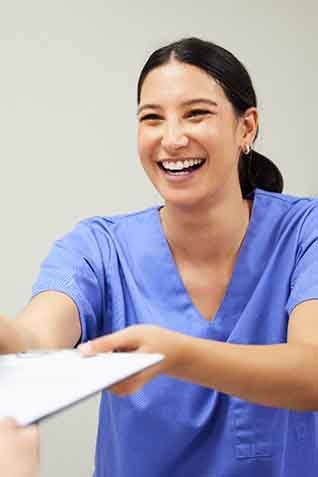 Dental assistant smiling while handing patient form