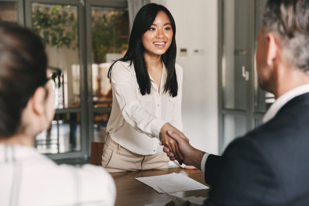 A woman shaking hands with a potential employer at a job interview.